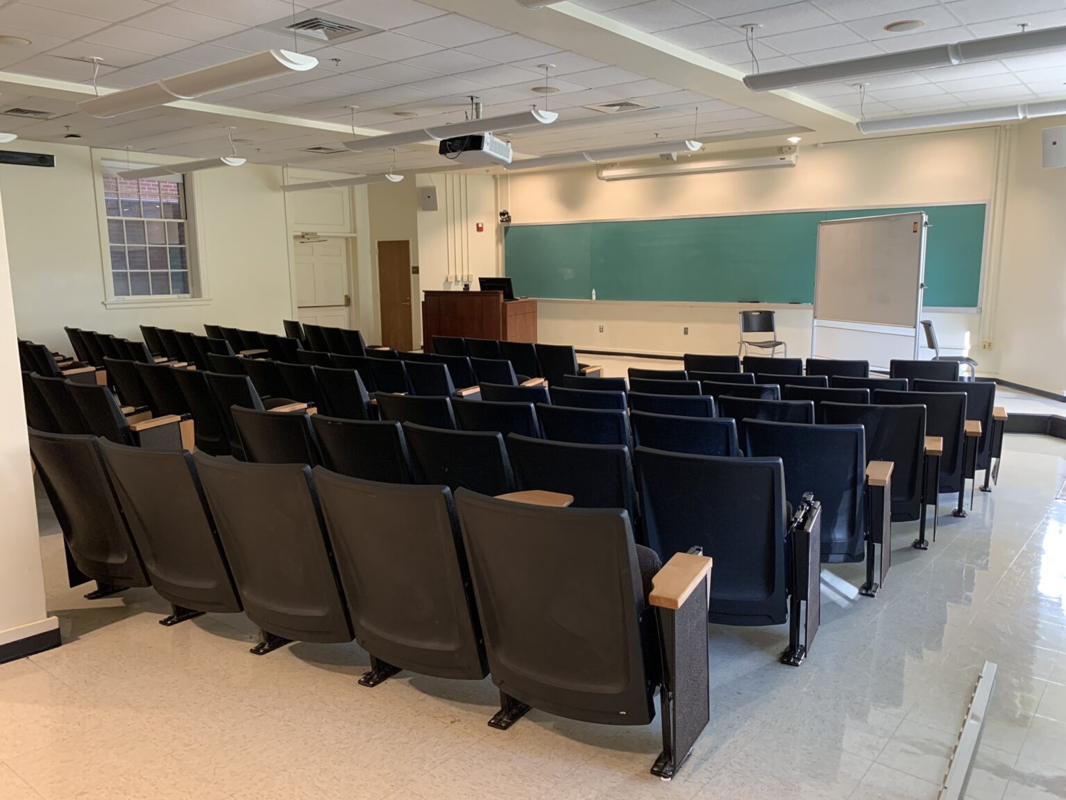Interior of a seminar room with rows of chairs facing a blackboard.